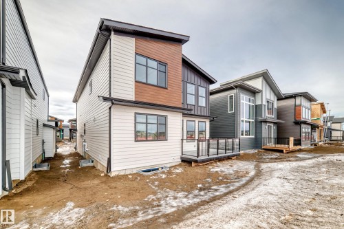 The property features modern architectural design with a blend of light and dark siding, and a deck with dark railings - 7665 Kimiwan Crescent, Edmonton, AB - Outdoor With Exterior