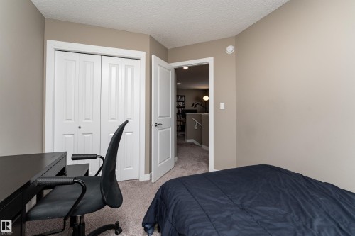 Bedroom with light carpet, a desk, a textured ceiling, and a closet - 1964 Kroetsch Crescent, Edmonton, AB - Indoor Photo Showing Bedroom
