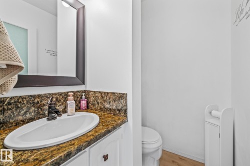 The bathroom features a vanity with a white oval sink set into a granite countertop and a dark framed mirror - 10940 Beaumaris Road, Edmonton, AB - Indoor Photo Showing Bathroom