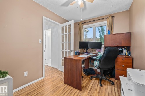 The property features light wood flooring, a ceiling fan, and a window providing natural light - 10940 Beaumaris Road, Edmonton, AB - Indoor Photo Showing Office