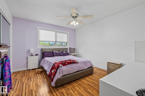 This inviting room features wood-look flooring, a window with blinds, and a ceiling fan with integrated lighting - 10940 Beaumaris Road, Edmonton, AB - Indoor Photo Showing Bedroom