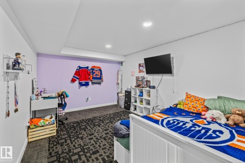 This room features a white bed frame, a wall-mounted television, and recessed lighting - 10940 Beaumaris Road, Edmonton, AB - Indoor