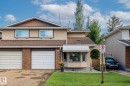 This property features a two-story exterior with a combination of stucco and brick finishes, a brown shingled roof, and a green lawn - 10940 Beaumaris Road, Edmonton, AB  - Outdoor 