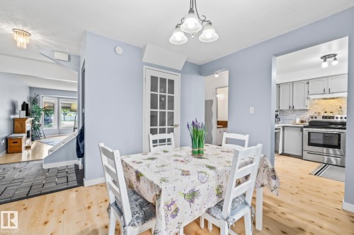 The dining area features light wood flooring and a chandelier - 10940 Beaumaris Road, Edmonton, AB - Indoor Photo Showing Dining Room
