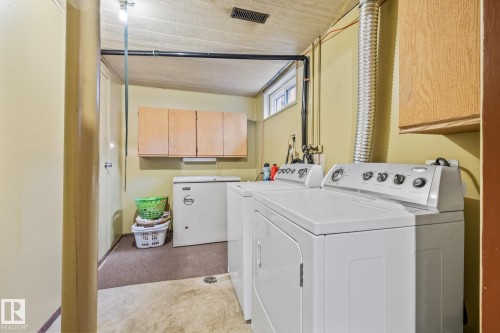 Laundry area featuring a window, light-colored walls, and overhead cabinetry - 10940 Beaumaris Road, Edmonton, AB - Indoor Photo Showing Laundry Room