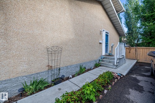 The property features stucco siding, a concrete pathway, and a well-maintained garden bed - 10940 Beaumaris Road, Edmonton, AB - Outdoor