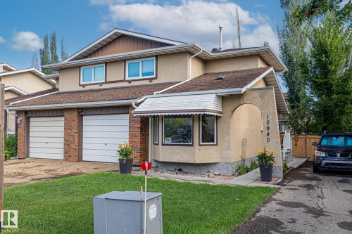 The property features a two-car garage with white doors and brick detailing, a front lawn, and a paved driveway - 10940 Beaumaris Road, Edmonton, AB - Outdoor