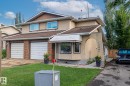The property features a two-car garage with white doors and brick detailing, a front lawn, and a paved driveway - 10940 Beaumaris Road, Edmonton, AB  - Outdoor 