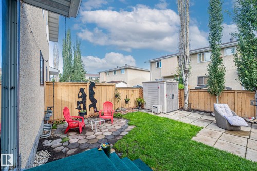 The property features a fenced yard with a combination of lawn, paving stones, and a hexagonal stone patio area - 10940 Beaumaris Road, Edmonton, AB - Outdoor