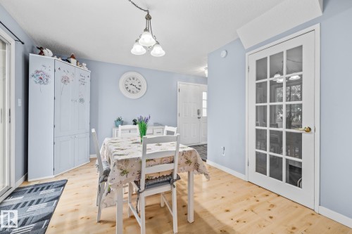 Dining area featuring light wood flooring, a ceiling-mounted light fixture, and a white French door with glass panels - 10940 Beaumaris Road, Edmonton, AB - Indoor Photo Showing Dining Room