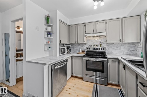 The kitchen features light-colored cabinetry with dark hardware, stainless steel appliances, and a tiled backsplash - 10940 Beaumaris Road, Edmonton, AB - Indoor Photo Showing Kitchen With Stainless Steel Kitchen With Upgraded Kitchen