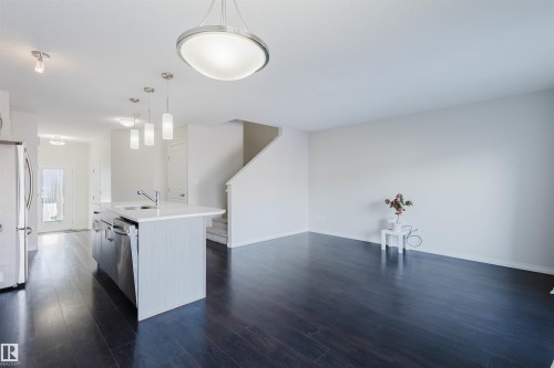Open concept living space featuring dark wood flooring, a kitchen island with sink and stainless steel appliances, and a staircase - 2082 Price Landing, Edmonton, AB - Indoor Photo Showing Kitchen