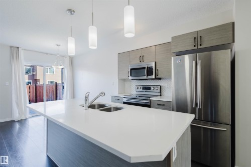 The kitchen features an island with a double sink, stainless steel appliances, and sleek cabinetry - 2082 Price Landing, Edmonton, AB - Indoor Photo Showing Kitchen With Stainless Steel Kitchen With Double Sink With Upgraded Kitchen
