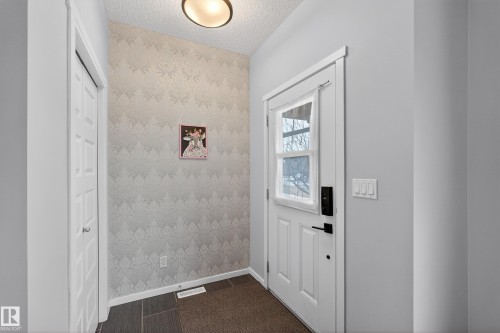 The entry features a white paneled door with a window, a light fixture, and patterned wallpaper - 1522 Chapman Way, Edmonton, AB - Indoor Photo Showing Other Room