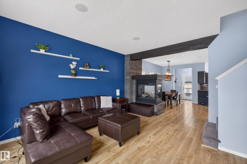 Living area featuring hardwood flooring, a stone-clad fireplace, and recessed ceiling lighting - 1522 Chapman Way, Edmonton, AB - Indoor Photo Showing Living Room With Fireplace