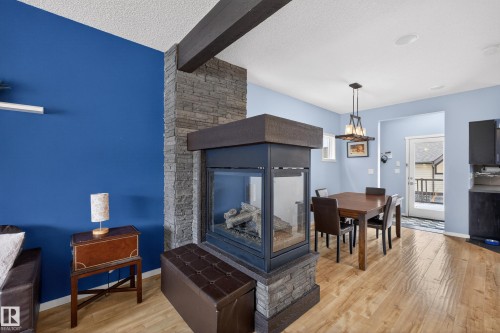 Living room with a stone-clad fireplace and a visible beam - 1522 Chapman Way, Edmonton, AB - Indoor With Fireplace