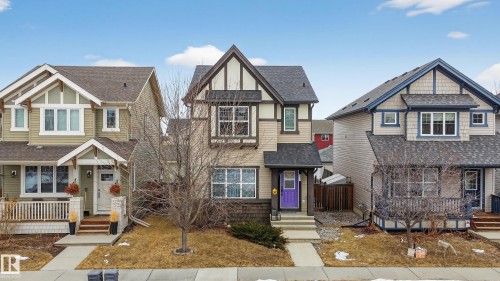 The property features a charming exterior with a purple front door, a prominent front gable, and a small front yard with a mature tree - 1522 Chapman Way, Edmonton, AB - Outdoor With Facade