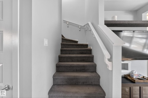 Carpeted staircase with white handrails and light gray walls - 1522 Chapman Way, Edmonton, AB - Indoor Photo Showing Other Room
