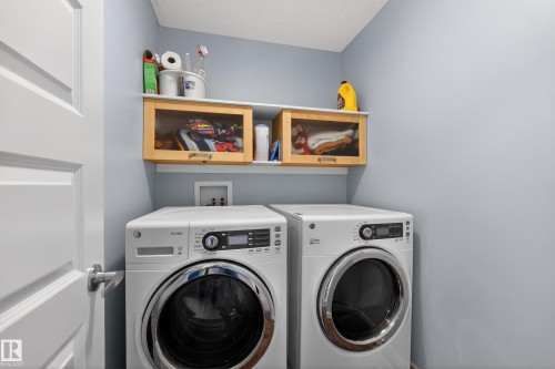 Dedicated laundry area with light blue walls and built-in wooden cabinetry - 1522 Chapman Way, Edmonton, AB - Indoor Photo Showing Laundry Room