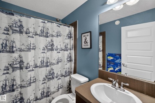 The bathroom features a vanity with a white sink and chrome faucet, a toilet, and a mirror with overhead lighting - 1522 Chapman Way, Edmonton, AB - Indoor Photo Showing Bathroom