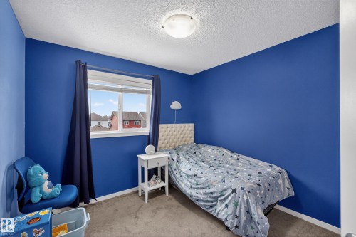 A room featuring a window with dark blue curtains, light grey carpet, and a light-colored ceiling - 1522 Chapman Way, Edmonton, AB - Indoor Photo Showing Bedroom