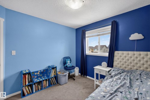 This room features light blue and dark blue painted walls, a textured white ceiling, and carpeted flooring - 1522 Chapman Way, Edmonton, AB - Indoor Photo Showing Bedroom