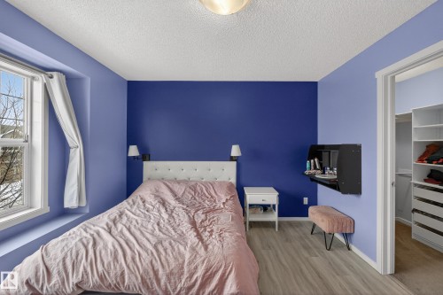 This room features light wood-style flooring, a window providing natural light, and a white tufted headboard - 1522 Chapman Way, Edmonton, AB - Indoor Photo Showing Bedroom