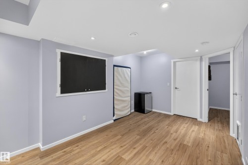 Spacious room featuring light wood-style flooring, light blue walls, and recessed lighting - 1522 Chapman Way, Edmonton, AB - Indoor Photo Showing Other Room