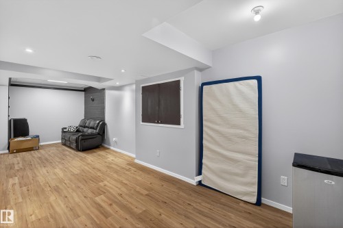 This open-plan area features a combination of recessed and flush-mount lighting, light-colored walls, and wood-look flooring - 1522 Chapman Way, Edmonton, AB - Indoor