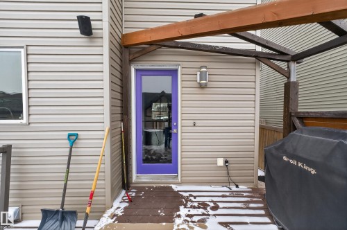 The property features a private deck with a purple exterior door, light beige siding, and an outdoor light fixture - 1522 Chapman Way, Edmonton, AB - Outdoor With Exterior