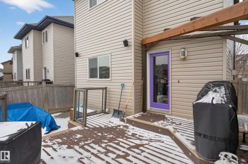 The property features a private deck with visible snow cover, a vivid purple exterior door, and light-colored siding - 1522 Chapman Way, Edmonton, AB - Outdoor With Exterior