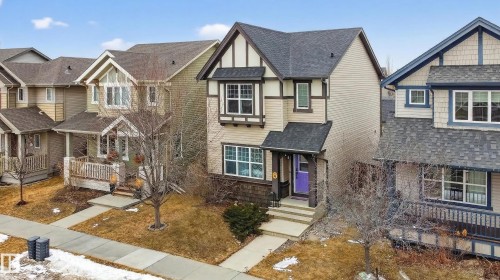 The property features a multi-level exterior with light-colored siding, dark trim, and a prominent front door with a distinctive purple hue - 1522 Chapman Way, Edmonton, AB - Outdoor With Facade