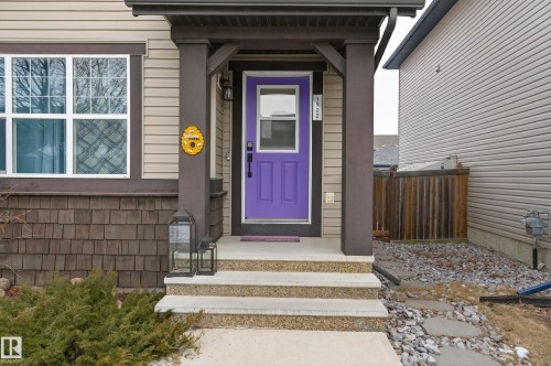 The property features a welcoming entrance with a vibrant purple door, concrete steps, and a covered porch - 1522 Chapman Way, Edmonton, AB - Outdoor