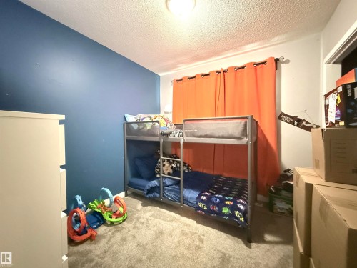 Room featuring a blue accent wall, neutral carpeting, and a window with orange curtains - 3912 108 Street, Edmonton, AB - Indoor