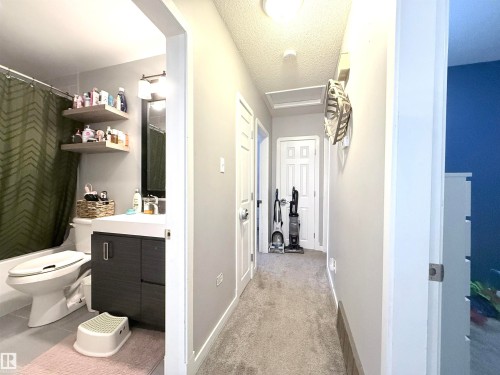 This property offers a hallway with light gray walls and a gray carpet, leading towards white doors - 3912 108 Street, Edmonton, AB - Indoor Photo Showing Bathroom