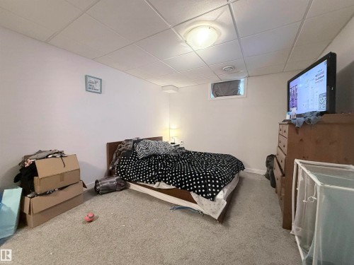 The room features carpeting, a drop ceiling, and a window providing natural light - 3912 108 Street, Edmonton, AB - Indoor Photo Showing Bedroom