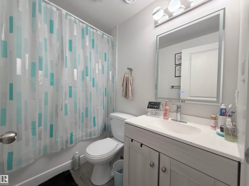The bathroom features a vanity with a white countertop and a mirror with integrated lighting - 3912 108 Street, Edmonton, AB - Indoor Photo Showing Bathroom