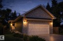 The property features a stone and siding exterior, a garage with a panel door, and a concrete driveway - 5851 Raven Crescent, Edmonton, AB  - Outdoor 