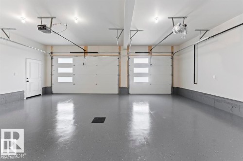 The property features a spacious garage with two overhead doors, each including frosted rectangular window inserts - 1410 Wildrye Crescent, Cold Lake, AB - Indoor Photo Showing Garage