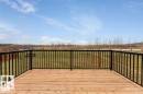 The property features a spacious wooden deck with black railings, overlooking a large grassy area with a wooden fence - 1410 Wildrye Crescent, Cold Lake, AB  - Outdoor 