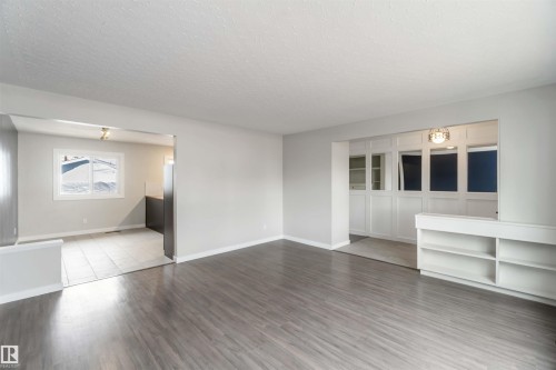 The property features light gray walls and dark gray flooring, with a built-in white shelving unit - 12121 38 Street, Edmonton, AB - Indoor