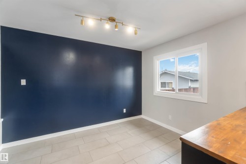This room features a window providing natural light, a dark accent wall, and light-colored tile flooring - 12121 38 Street, Edmonton, AB - Indoor Photo Showing Other Room