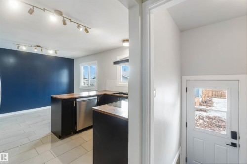 The property features a kitchen with dark cabinetry, light-colored countertops, and a stainless steel dishwasher - 12121 38 Street, Edmonton, AB - Indoor