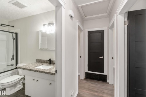 The bathroom features a modern vanity with a granite countertop, a shower-over-tub combination with a glass enclosure, and a contemporary light fixture - 12121 38 Street, Edmonton, AB - Indoor Photo Showing Bathroom