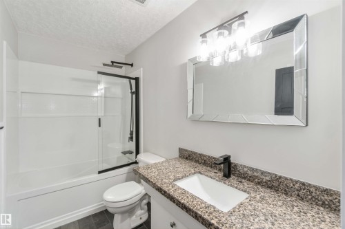 The bathroom features a modern vanity with a granite countertop and an undermount sink - 12121 38 Street, Edmonton, AB - Indoor Photo Showing Bathroom