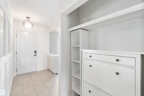 The property features a bright entryway with a paneled door, a decorative overhead light fixture, and tiled flooring - 12121 38 Street, Edmonton, AB - Indoor Photo Showing Other Room