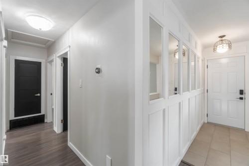 The property features a hallway with dark wood-style flooring and light-colored walls - 12121 38 Street, Edmonton, AB - Indoor Photo Showing Other Room