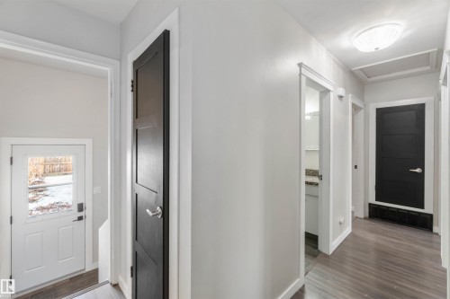 The property features a bright hallway with light-colored walls and dark wood-look flooring - 12121 38 Street, Edmonton, AB - Indoor Photo Showing Other Room