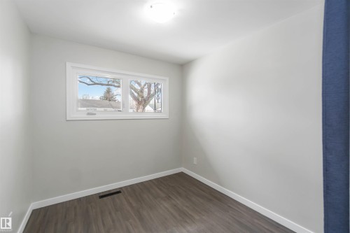 Room featuring light gray walls, dark wood-style flooring, and a window providing natural light - 12121 38 Street, Edmonton, AB - Indoor Photo Showing Other Room
