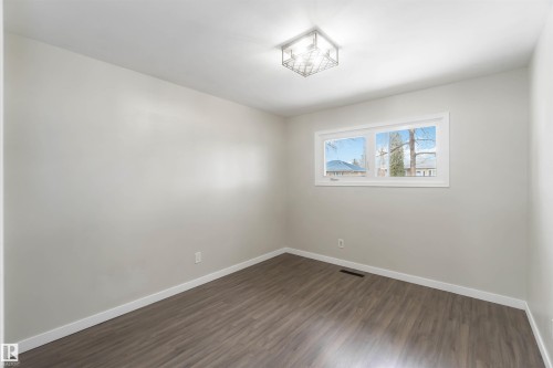 This room features light-colored walls, wood-style flooring, and a ceiling light fixture - 12121 38 Street, Edmonton, AB - Indoor Photo Showing Other Room